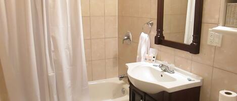 A bathroom with a bathtub, a sink, a mirror, and a toilet.
