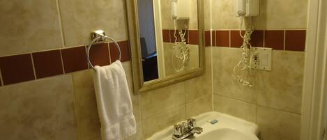 A bathroom with a sink, a mirror, a towel rack, and a hairdryer.