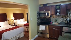 A hotel room with a bed, bedside tables, a microwave, a stove, and a sink in the kitchenette. - Bayside Inn & Waterfront Suites (Kingston)