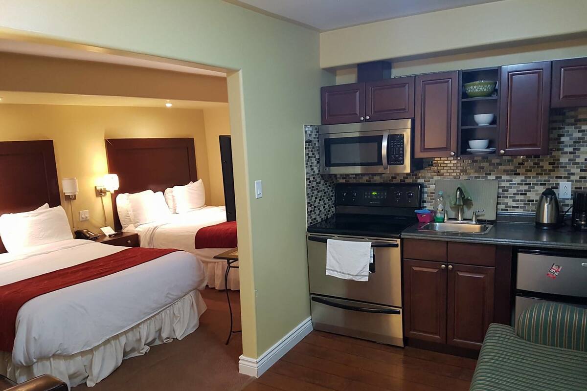 Une chambre d’hôtel équipée d’un lit, de tables de chevet, d’un four à micro-ondes, d’une cuisinière et d’un évier dans la kitchenette.