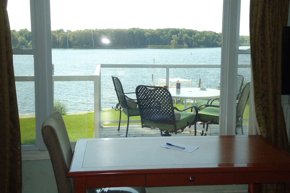Un balcon avec une table et des chaises donnant sur un lac.