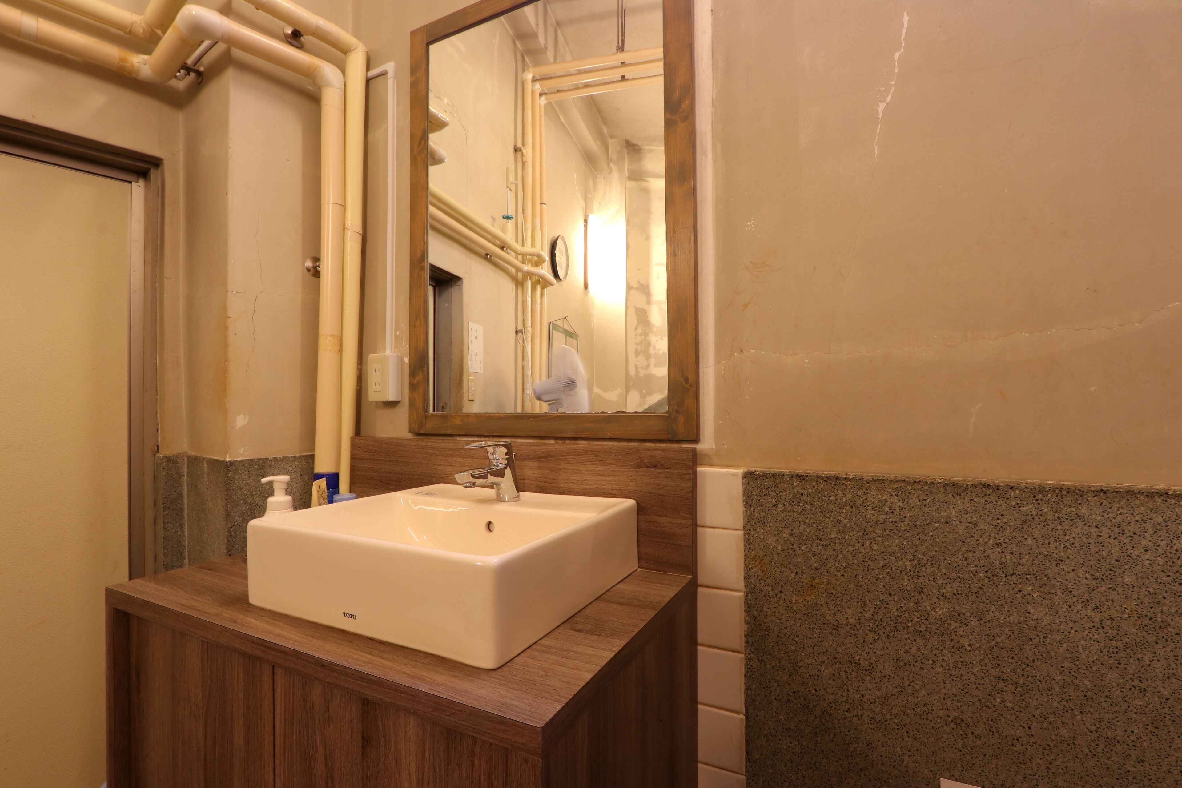 A bathroom with a white sink, wooden vanity, and a mirror.