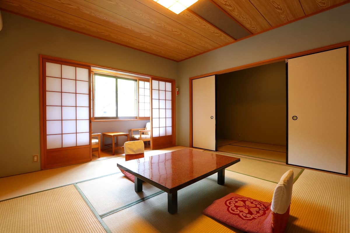 A traditional Japanese room with tatami flooring, a low table, and sliding doors.