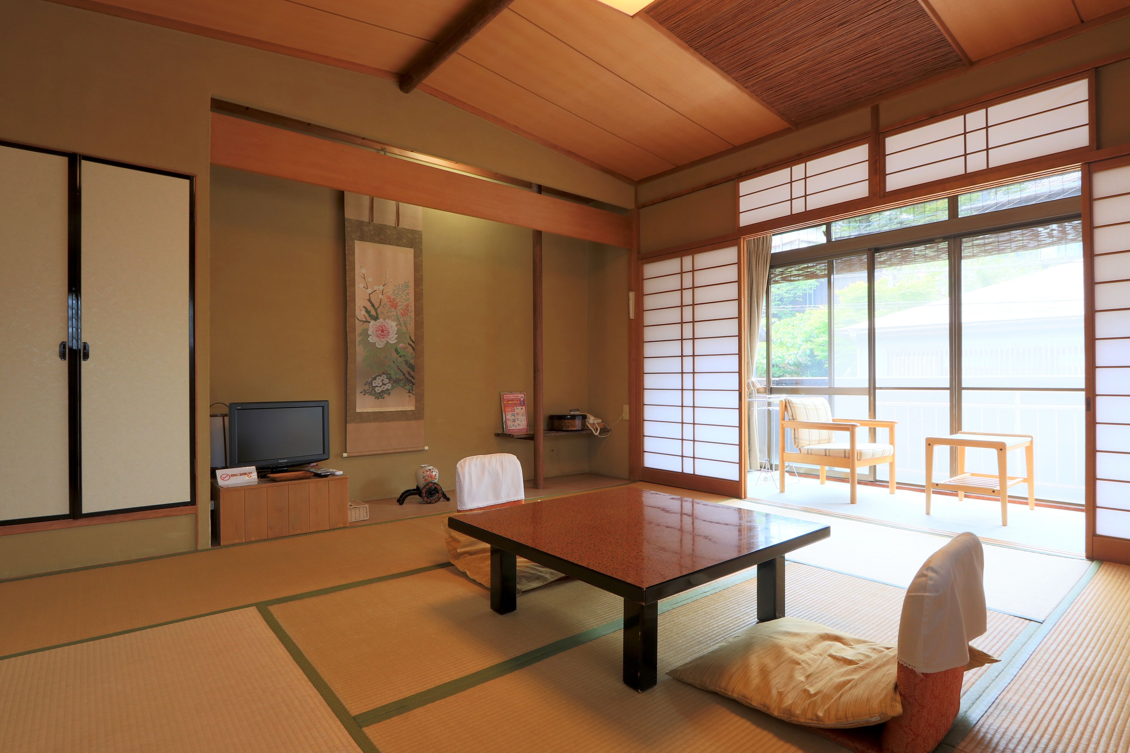 A traditional Japanese room with tatami flooring, a low table, a television, and sliding doors.