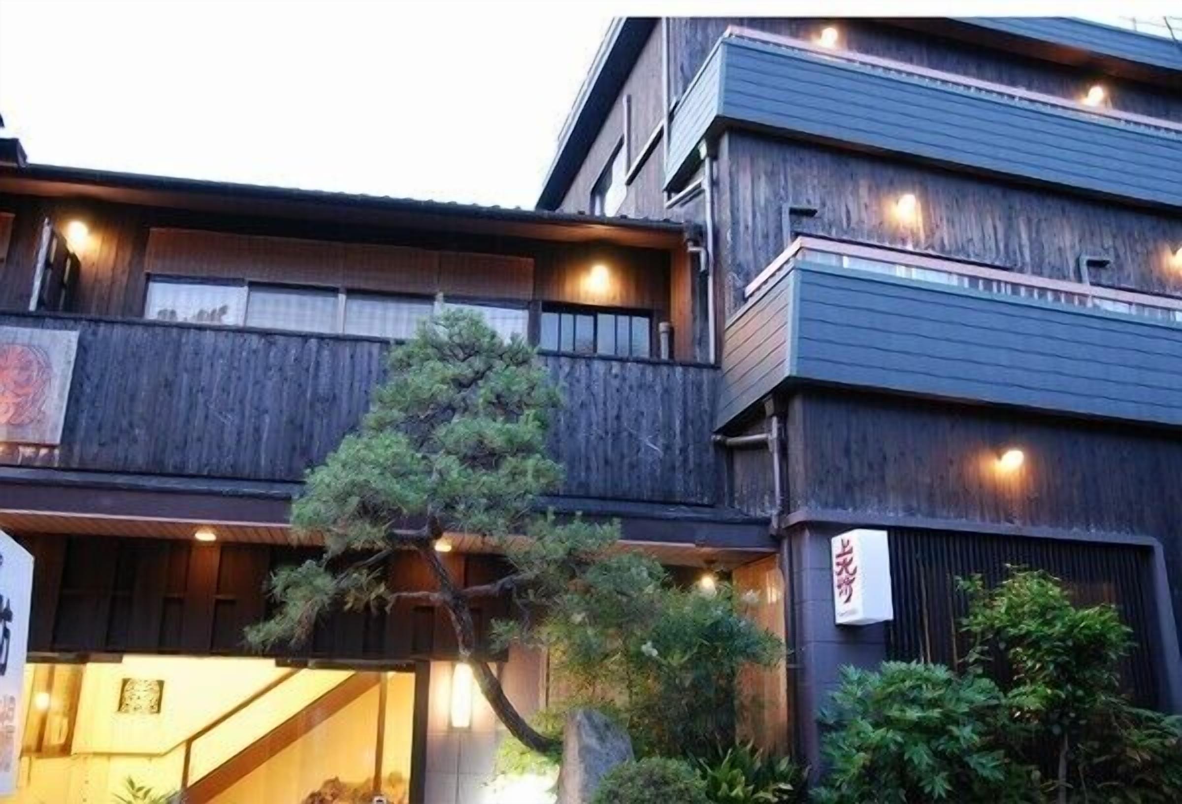 A multi-story building with a wooden facade, a visible entrance, and a sign with Japanese characters.