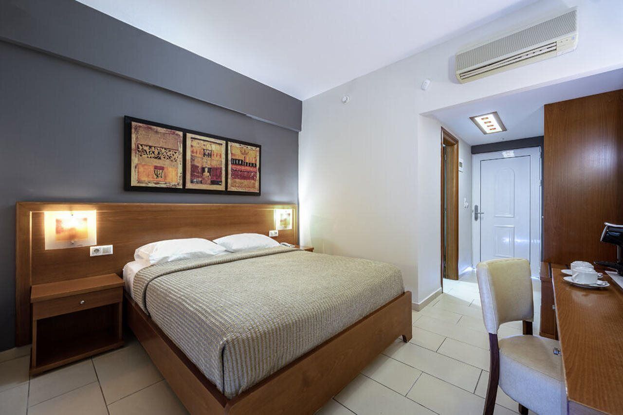 Habitación de hotel con cama, mesitas de noche, un escritorio con silla y una obra de arte en la pared.