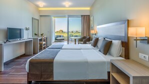 Ein modernes Hotelzimmer mit einem großen Bett, einem Schreibtisch, einem Fernseher und Blick ins Freie.