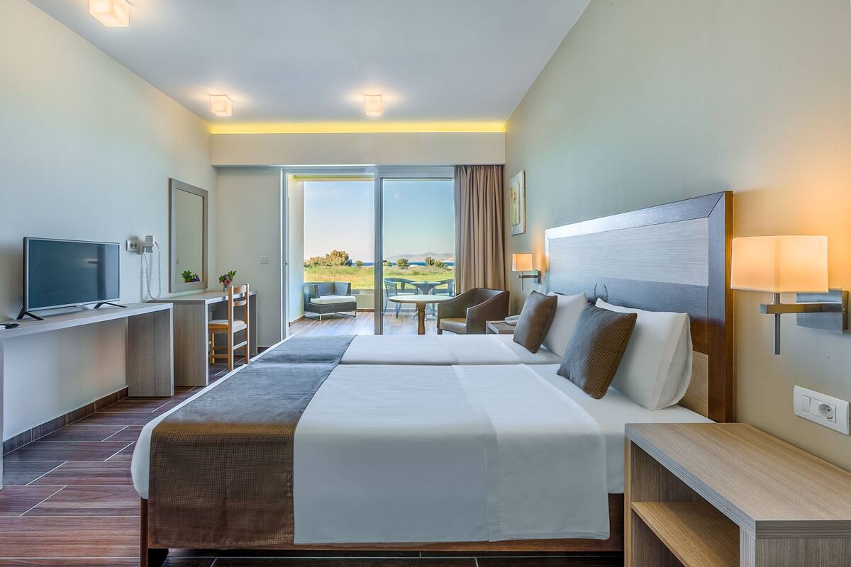 Une chambre d’hôtel moderne dotée d’un grand lit, d’un bureau, d’une télévision et offrant une vue sur l’extérieur.