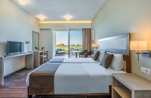 Habitación de hotel moderna con una cama grande, un escritorio, un televisor y vistas al exterior.