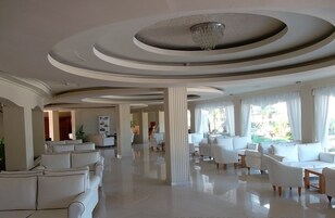 Un vestíbulo amplio con techo alto, candelabros modernos y una variedad de zonas de estar con sofás y sillones.
