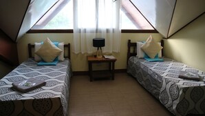 Une chambre avec deux lits, une petite table avec une lampe et une fenêtre ornée de rideaux légers.