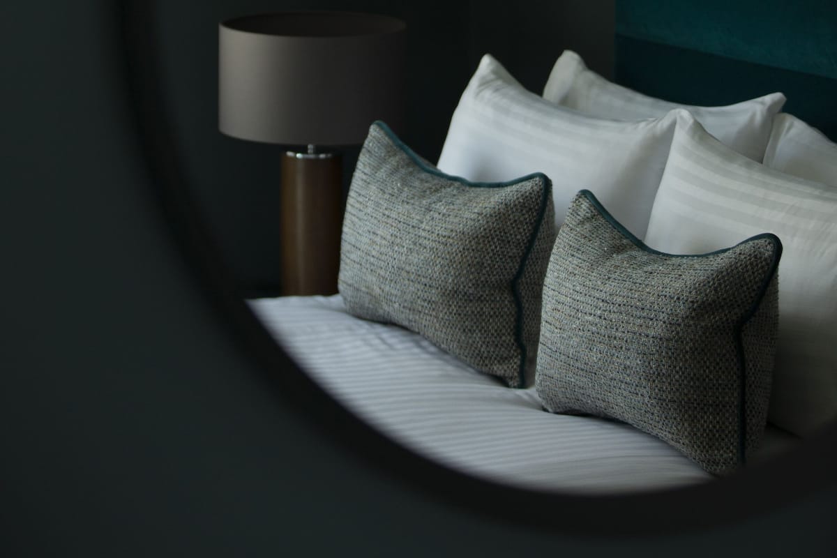 Une chambre à coucher avec un lit, des oreillers, une lampe et une tête de lit.