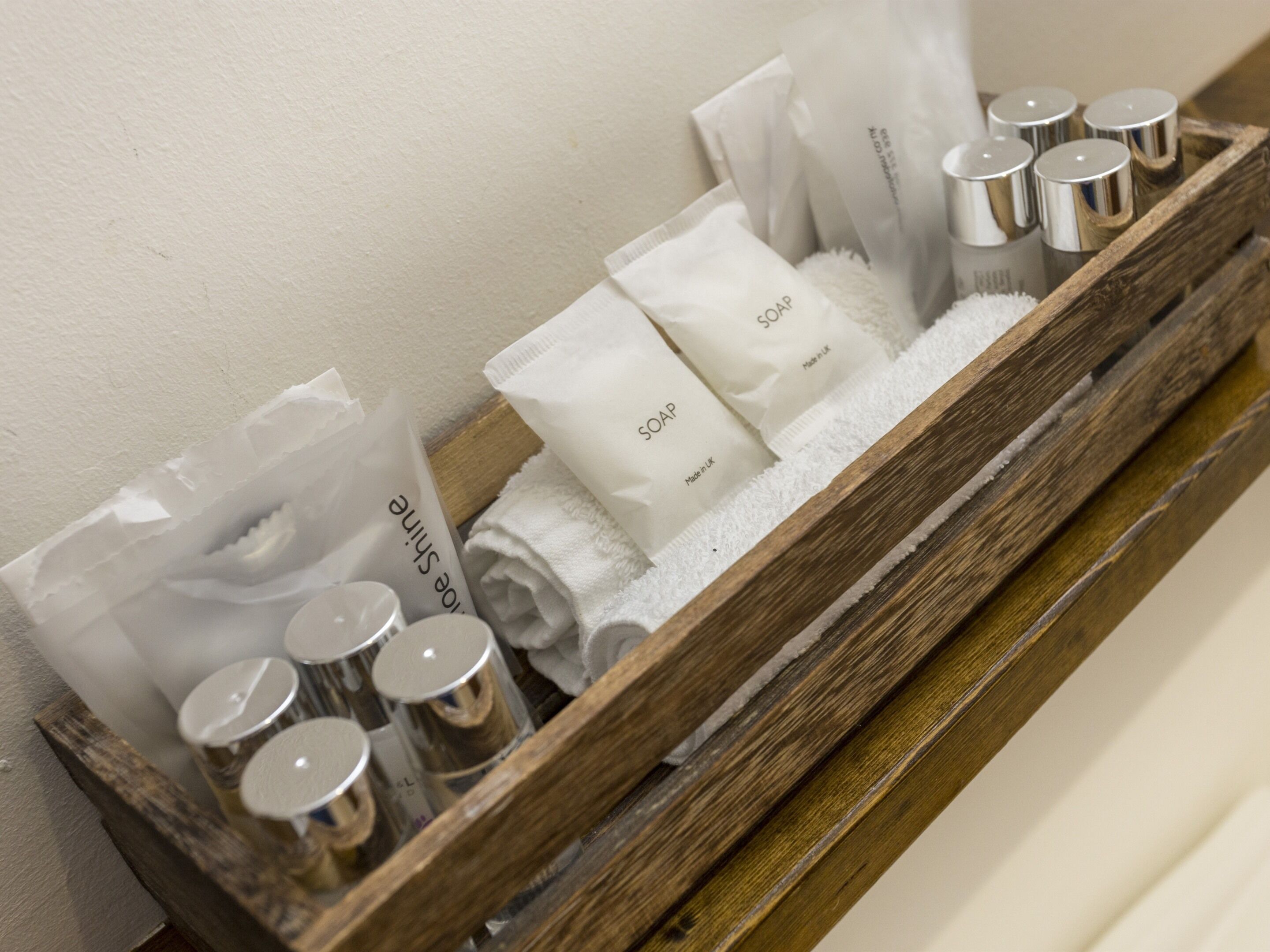 A wooden tray with toiletries including soap, a toothbrush, and a towel.