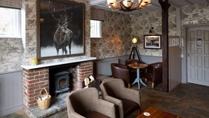 A cozy room with a fireplace, a large deer painting, and a chandelier.