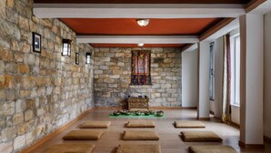 A room with stone walls, a wooden floor, and a central altar with ritual items.