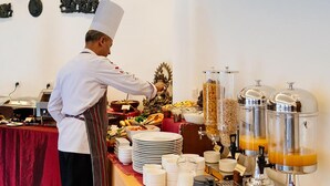 A buffet setup with a chef serving food, a variety of dishes, and self-serve beverage dispensers.