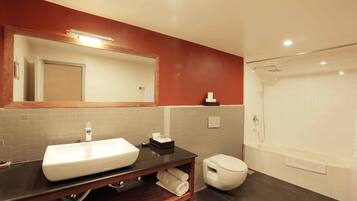 A modern bathroom with a large mirror, a white sink, a toilet, and a bathtub.