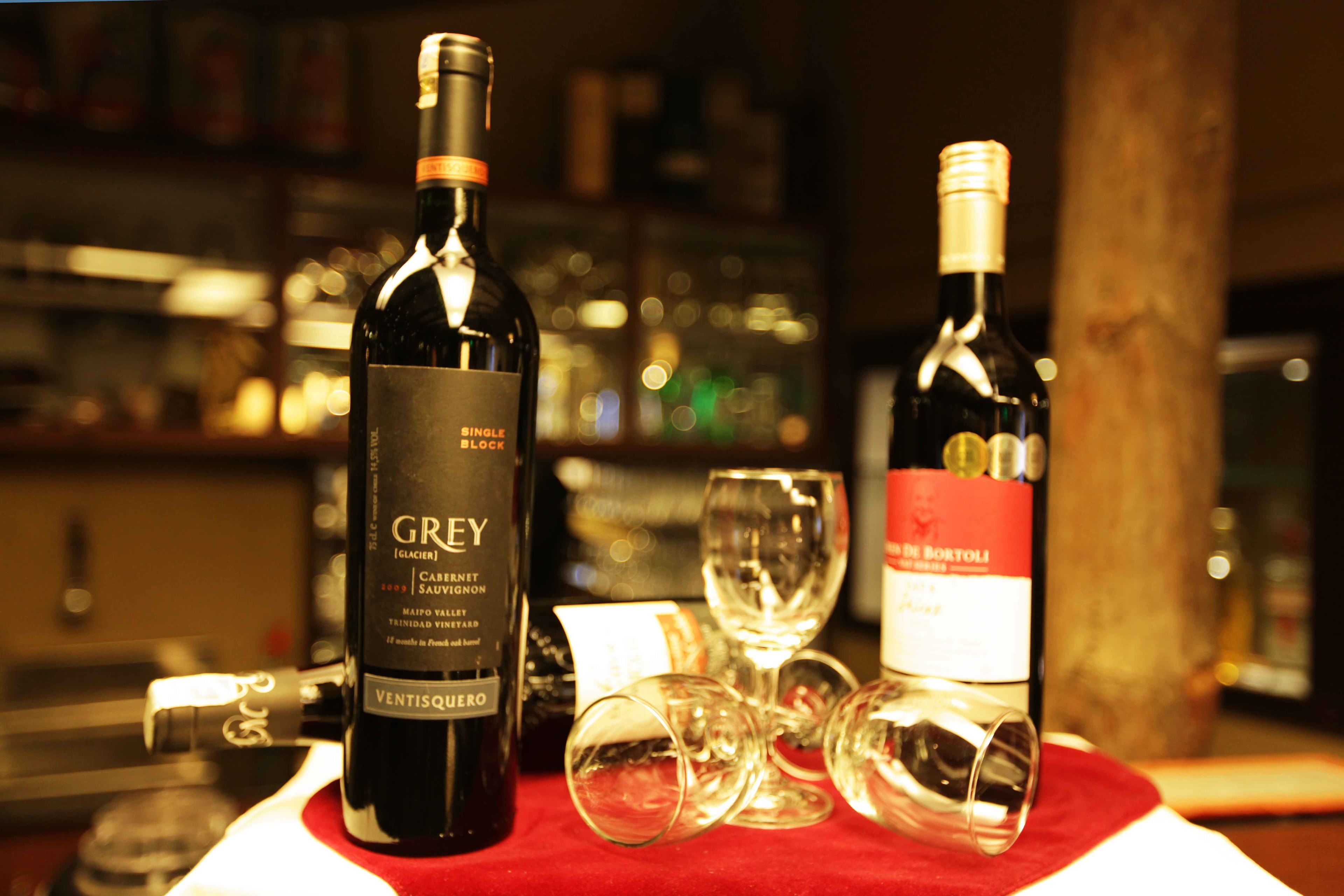 Two wine bottles and several wine glasses on a table.