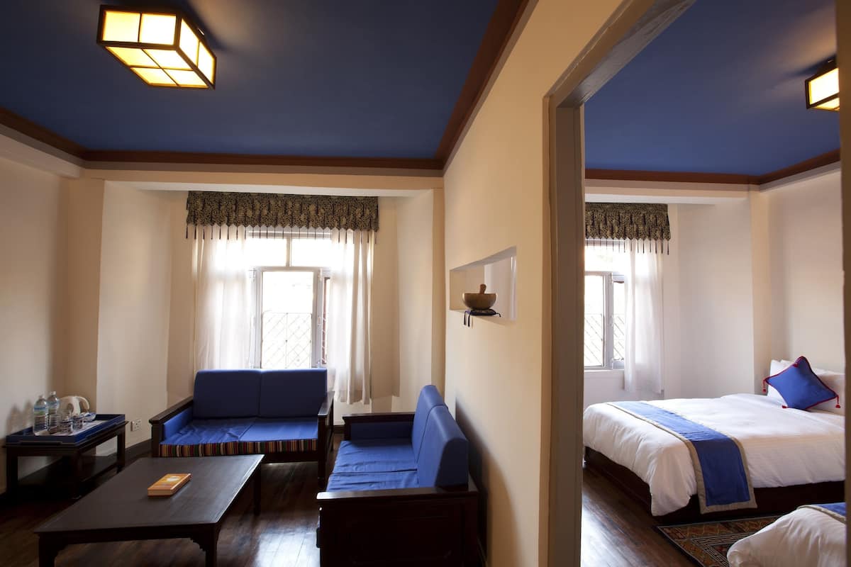 Een hotelkamer met een bank, een bed, een klein tafeltje en een raam met gordijnen.