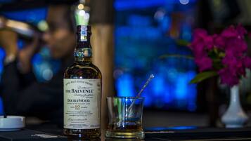 Eine Flasche The Balvenie DoubleWood Whisky und ein Glas mit Trinkhalm auf einer Bar.