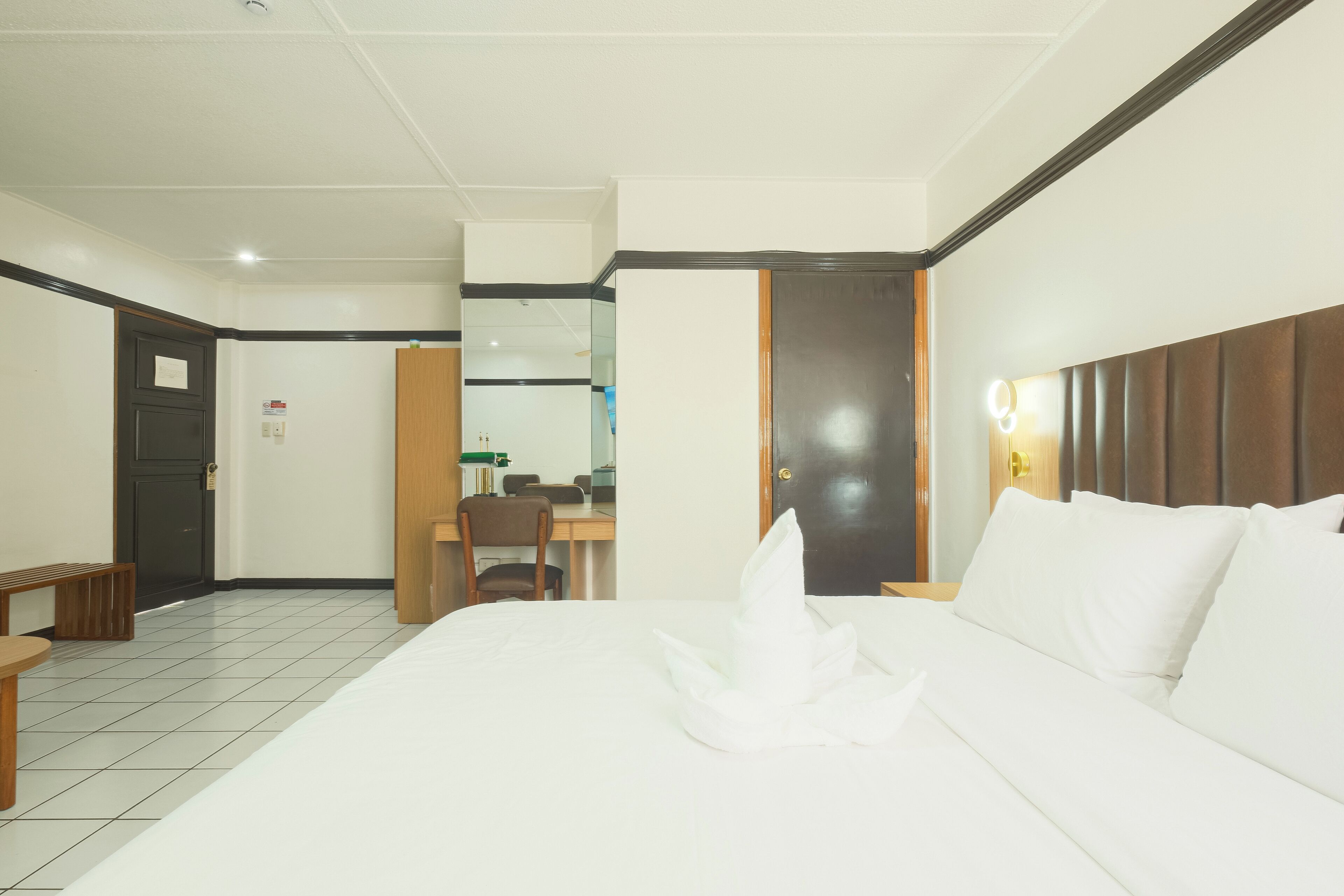 A hotel room with a bed, a desk, and a chair.