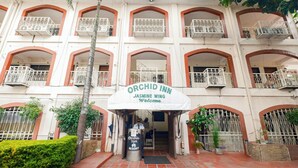 Ein mehrstöckiges Gebäude mit Balkonen und einem Schild mit der Aufschrift 'Orchid Inn Jasmine Wing Welcome'.