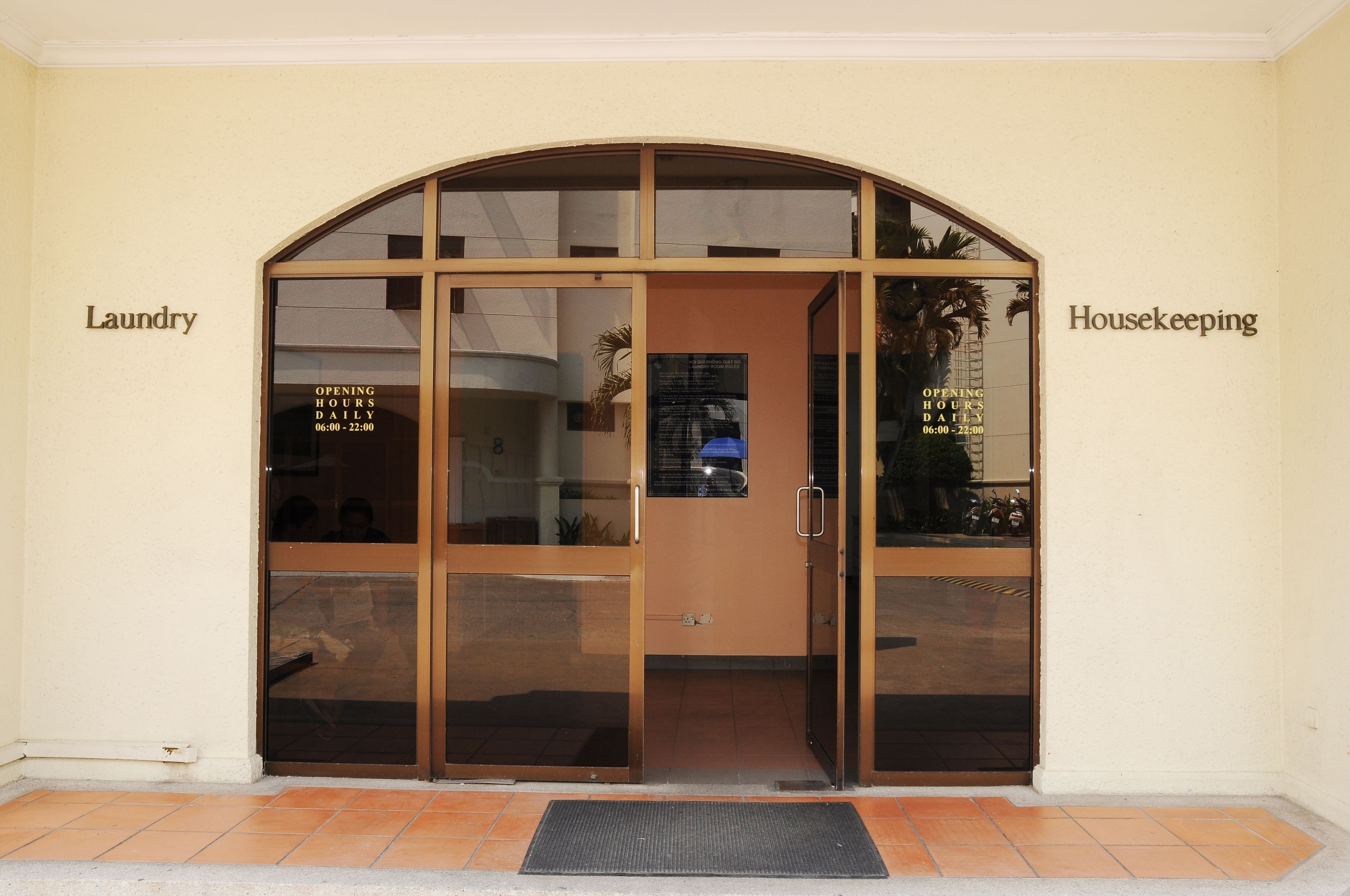 A hotel entrance with a glass door and a sign indicating 'Laundry' and 'Housekeeping' services.