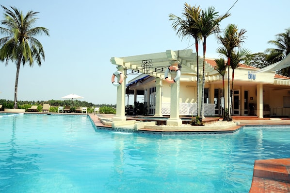 Una piscina al aire libre, sillones reclinables de piscina