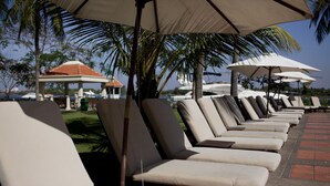 A row of sun loungers under umbrellas, a palm tree, and a gazebo in the background. - Riverside Serviced Apartments (Ho Chi Minh City)