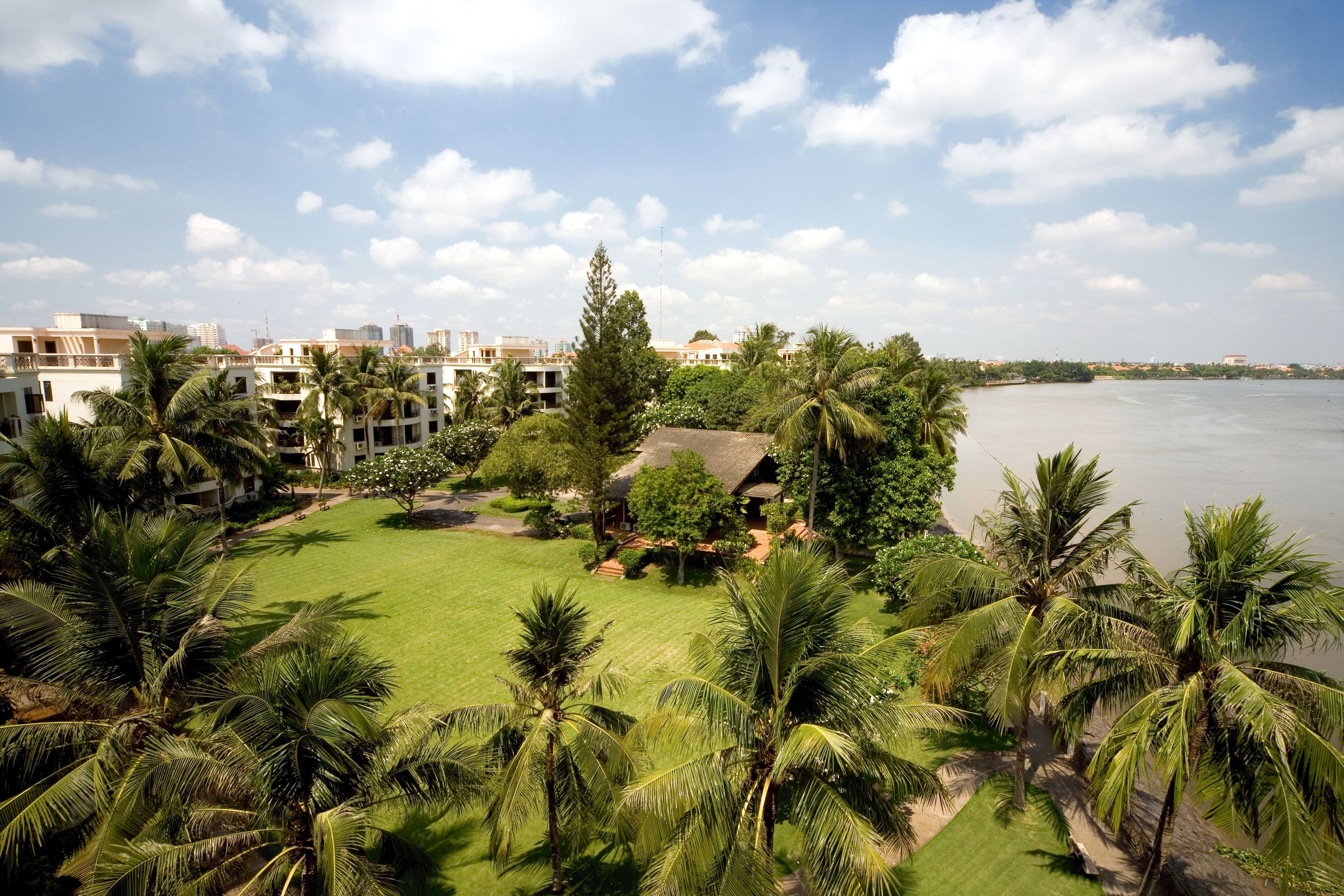 A resort with a pool, palm trees, and a view of the water.