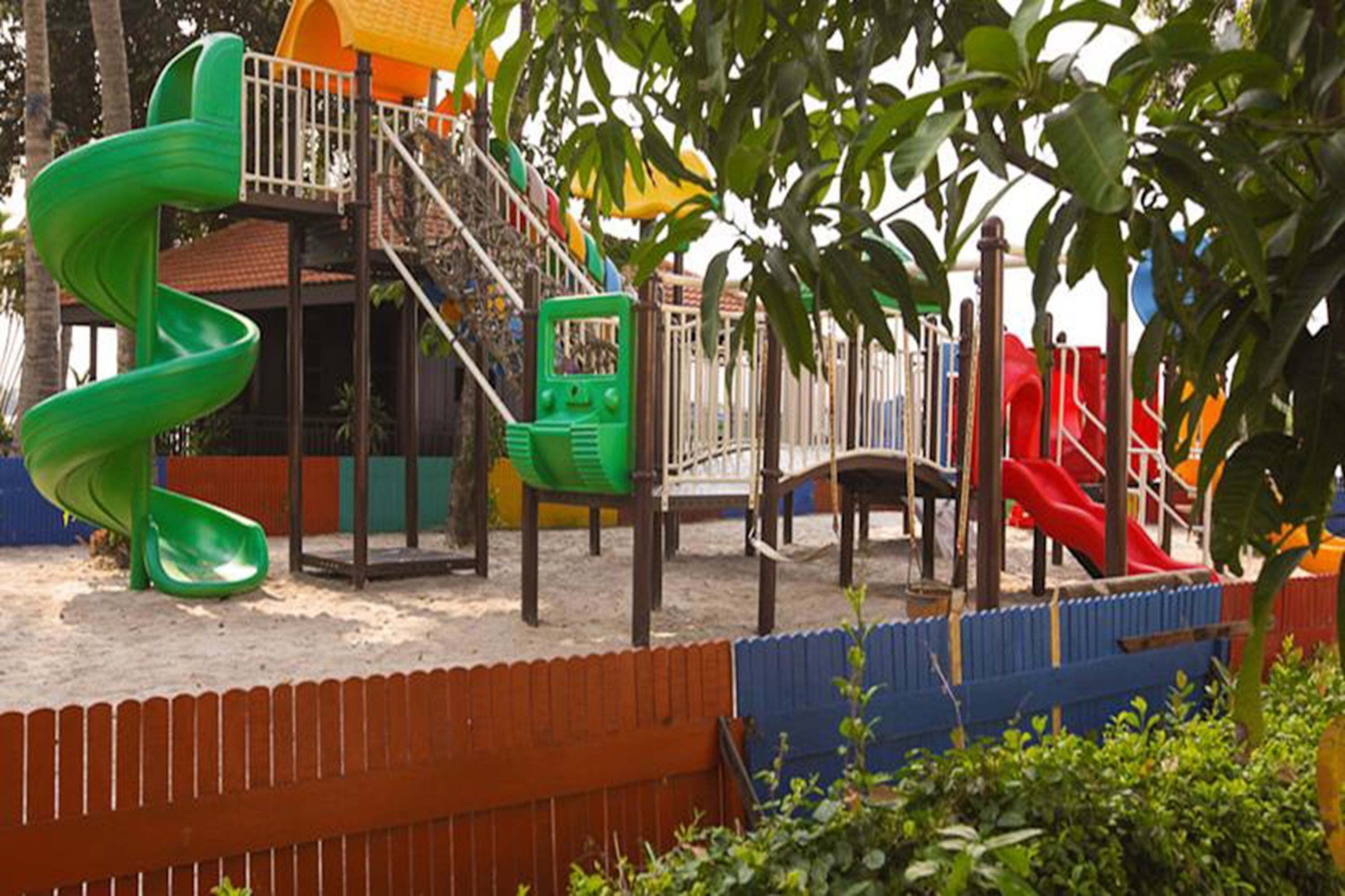 A playground with a green spiral slide, a red slide, and a climbing structure.