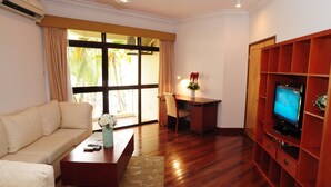 A living room with a sofa, coffee table, TV stand, and a dining area with a table and chairs. - Riverside Serviced Apartments (Ho Chi Minh City)