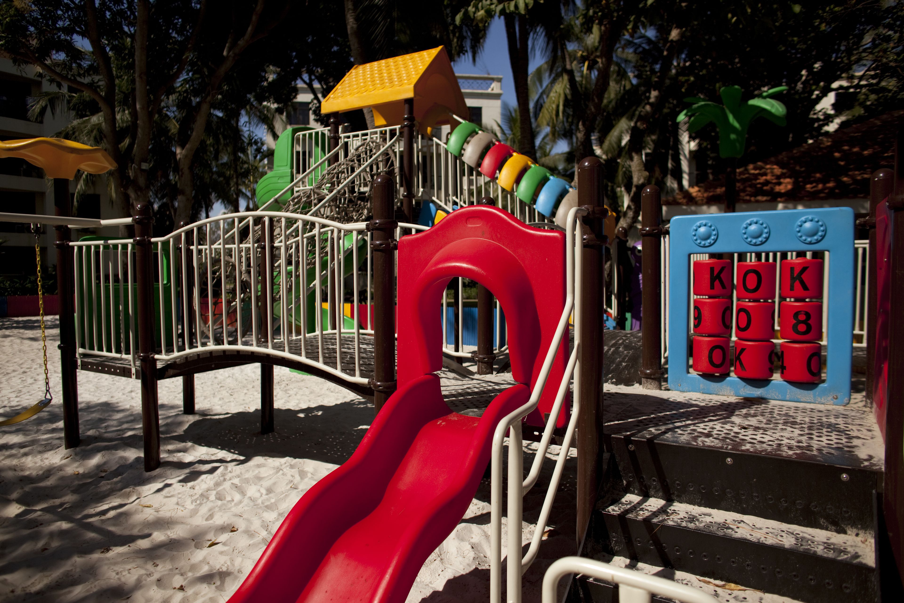 Ein Spielplatz mit einer roten Rutsche, einer Kletterkonstruktion und einem Spielbereich mit nummerierten Bauklötzen.