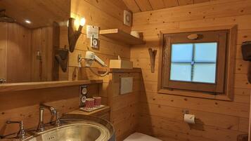 Un baño de cabaña de madera con lavamanos, inodoro y ventana.