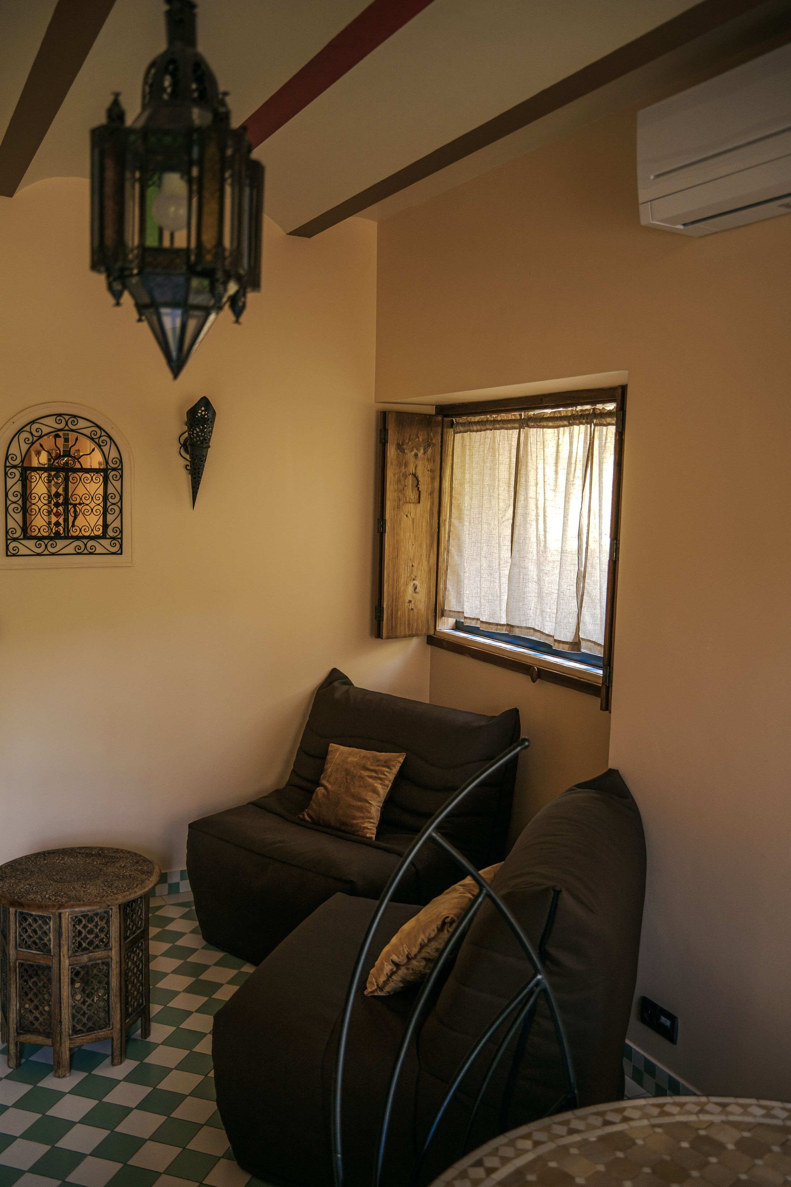 Una habitación acogedora con piso a cuadros, un rincón de descanso con cojines y un ventanal, además de un adorno en la pared.