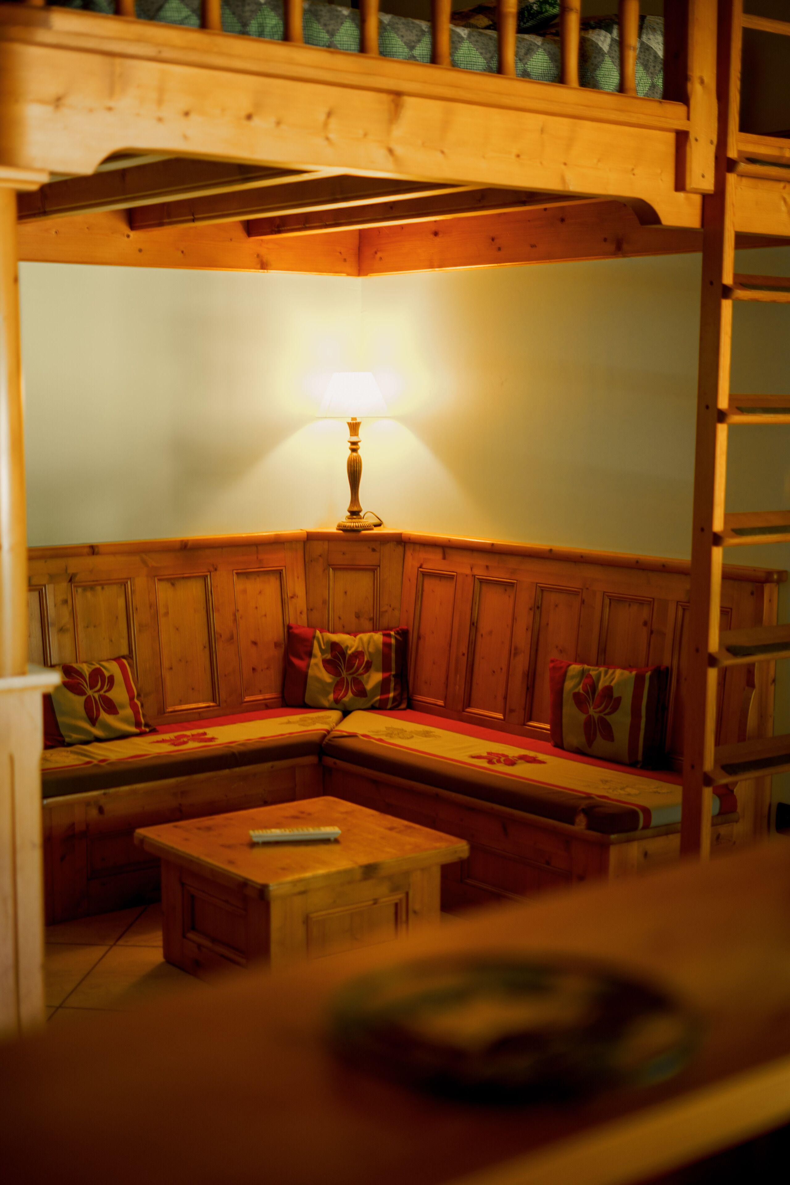 Une pièce chaleureuse avec un banc en bois, une table et une lampe.