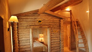 A log cabin-style room with a bed, a nightstand with a lamp, a wooden ladder, and a bear warning sign. - Valsoyo (Upie)