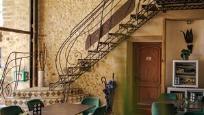 A dining area with a stone wall, a staircase, and green chairs. - Valsoyo (Upie)