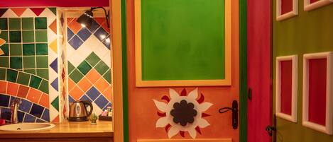 A kitchen with a colorful door, a tiled backsplash, and wooden cabinets.