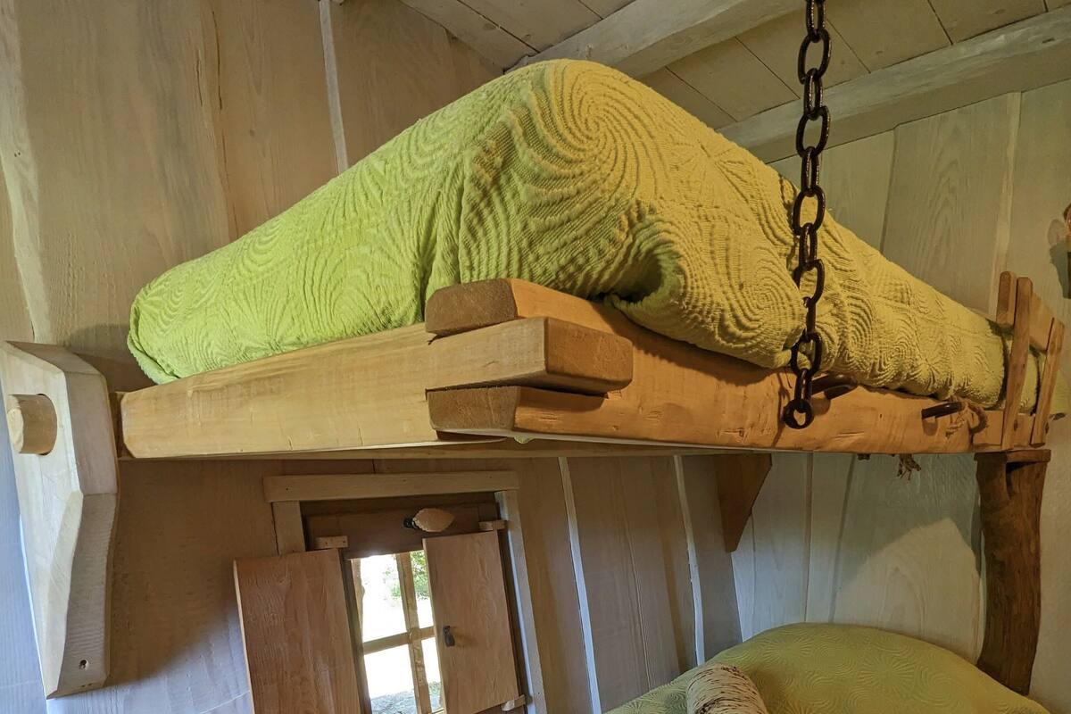 A bunk bed with a green blanket and a wooden headboard.