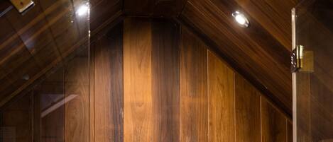 A wooden shower enclosure with a handheld showerhead and a wall-mounted faucet.