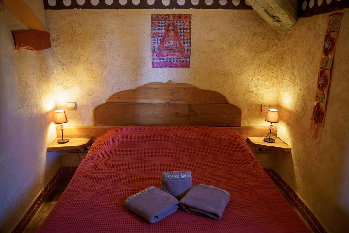 A bed with a red bedspread, two bedside lamps, and a wooden headboard.