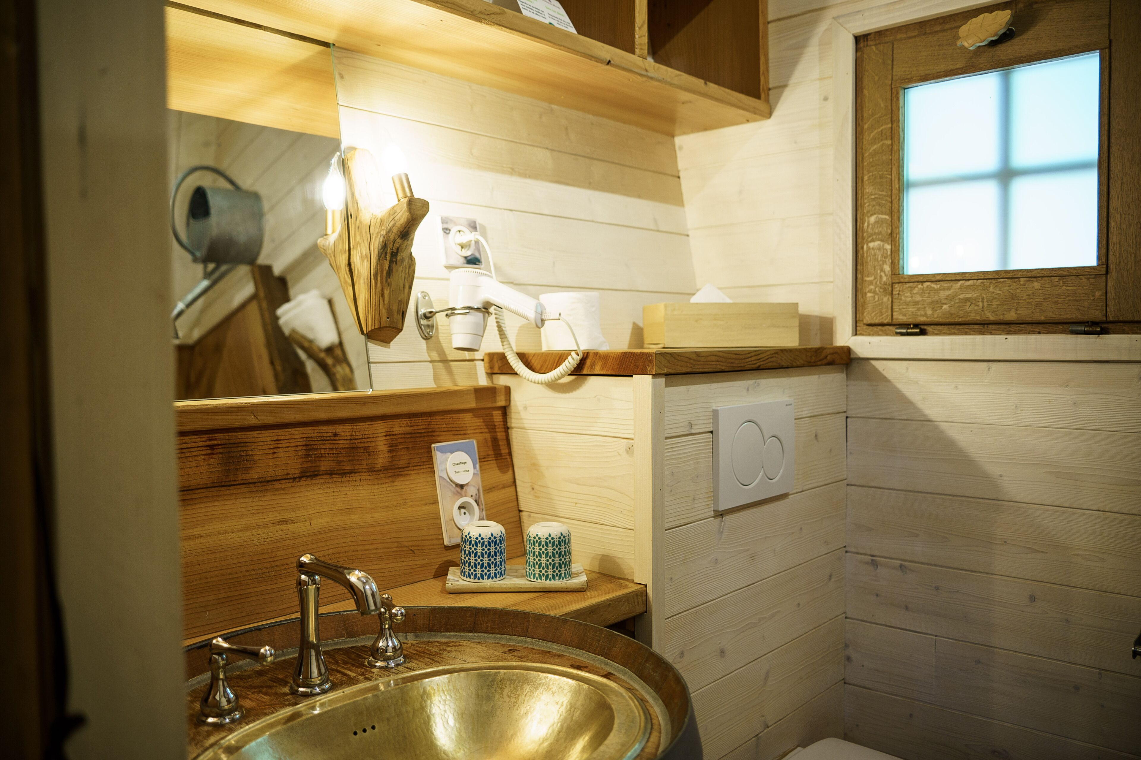 Baño de cabaña de madera con lavamanos, espejo y toallero.