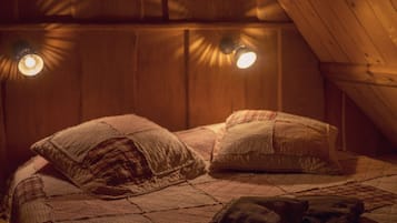 Une chambre confortable située sous les toits, avec un plafond en bois, une couvre-lit matelassé et deux lampes de chevet.