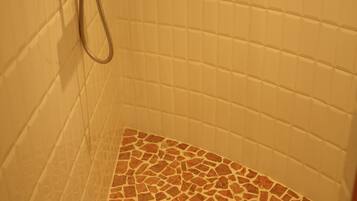 A shower with a tiled wall and a mosaic floor.