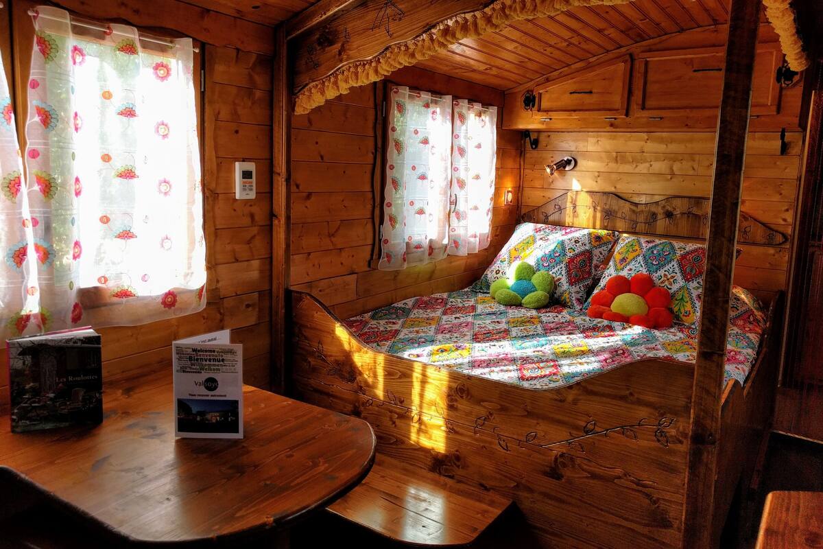 A cozy cabin-style room with wooden walls and a bed with a colorful quilt.