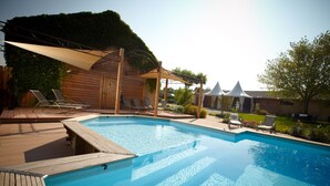 A swimming pool with wooden deck and lounge chairs, surrounded by a wooden cabin and a covered area with a white canopy. - Valsoyo (Upie)