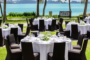 A series of round tables set up outdoors with white tablecloths, black chairs, and floral centerpieces. - Paradise Suites Hotel (Ha Long)