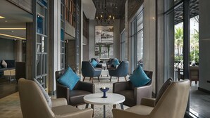 Een ruime lobby met lederen fauteuils, een ronde tafel en een kroonluchter.