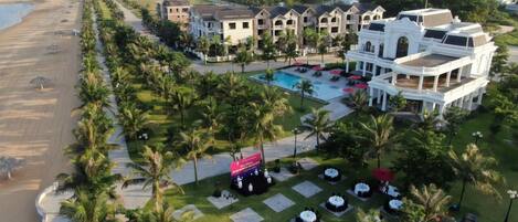 Ein Resort mit Pool, Sitzgelegenheiten im Freien und Blick auf den Strand.